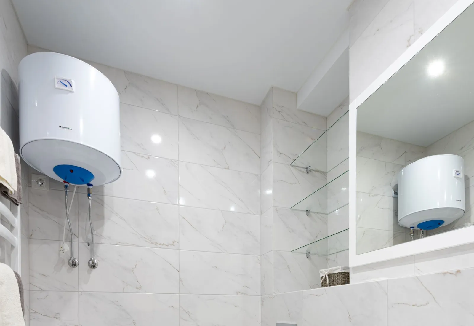 Electric water heater cylinder above a bathroom basin
